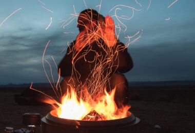 man sitting facing fire in pot during night