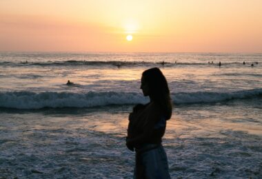 woman with baby on beach at sunset