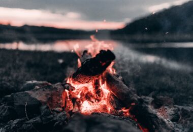 bright bonfire near lake and mountains at night
