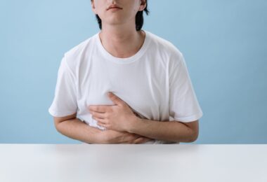 man in white shirt suffering from a stomach pain