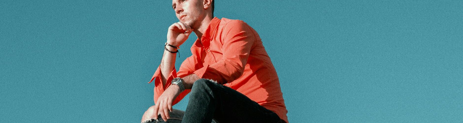 pensive man sitting on mountain peak