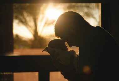 man carrying baby drawing their foreheads